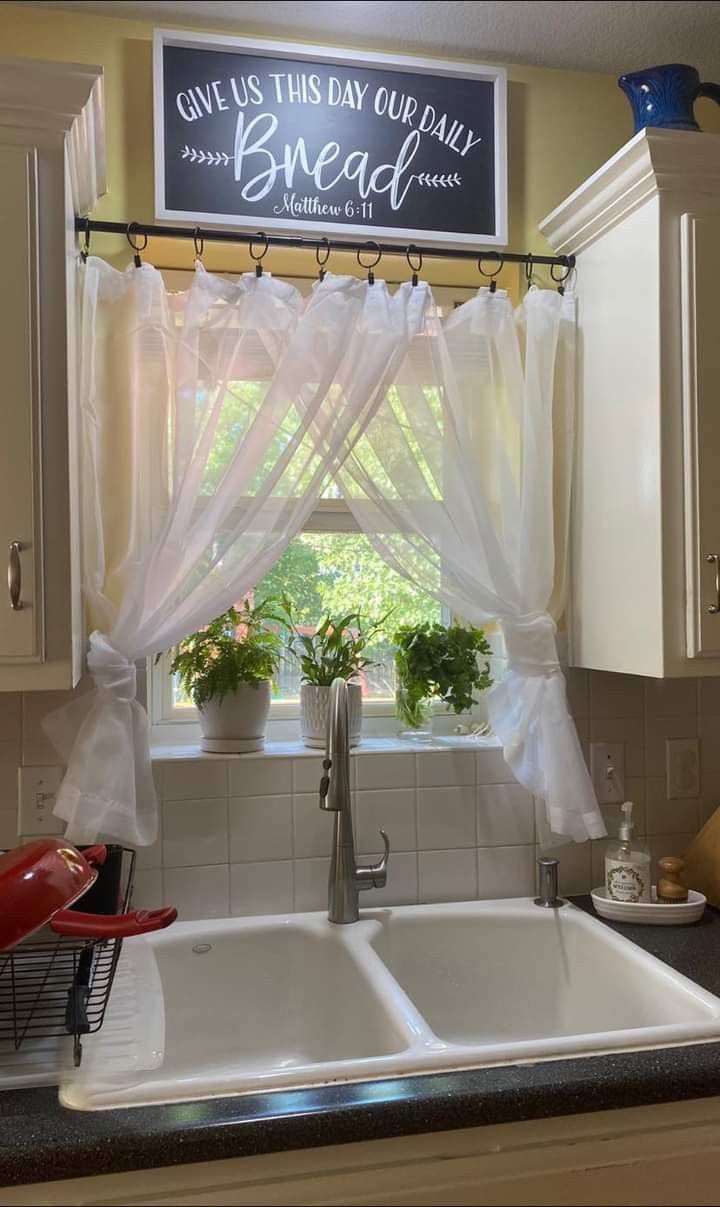 a kitchen sink under a window with curtains