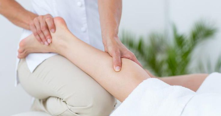 a woman getting a foot massage in a spa room with her hands on the leg