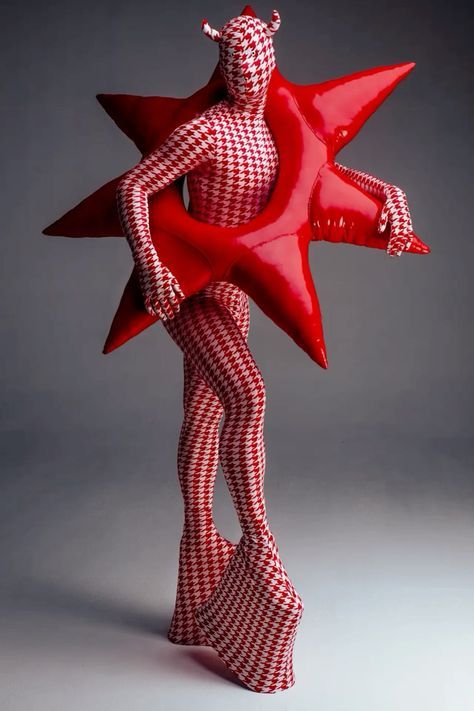 a red and white figurine holding a star shaped object in the shape of a woman