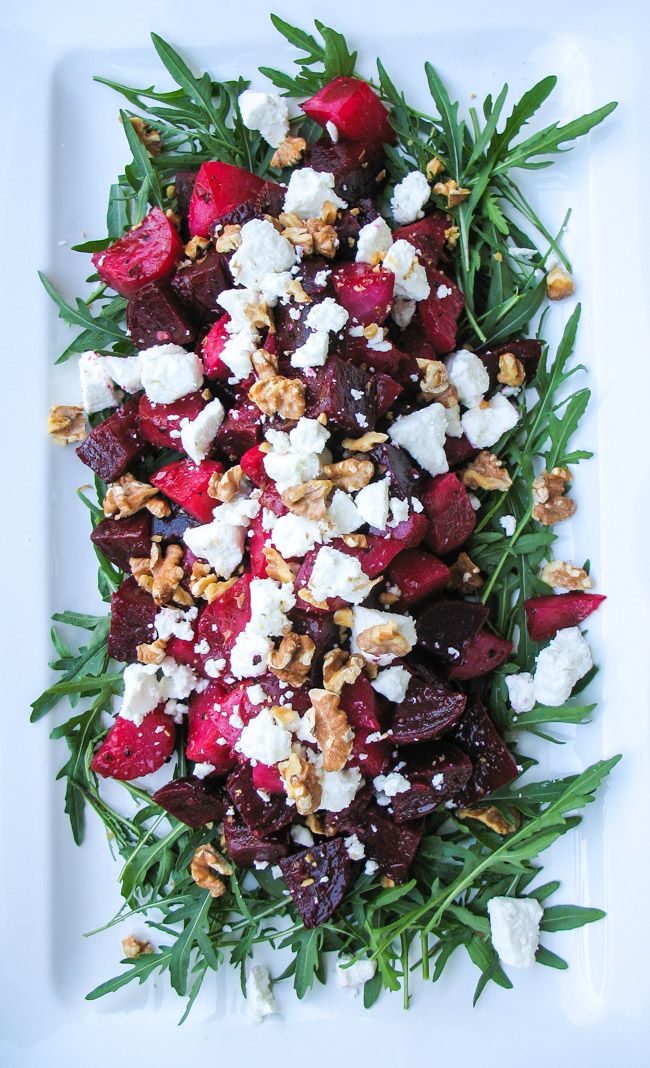 beet and goat cheese salad on a white plate with green garnishes