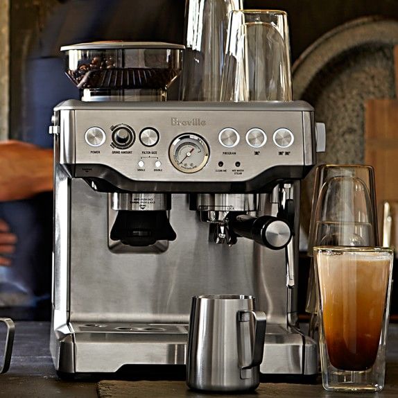 an espresso machine sitting on top of a counter next to a glass filled with liquid