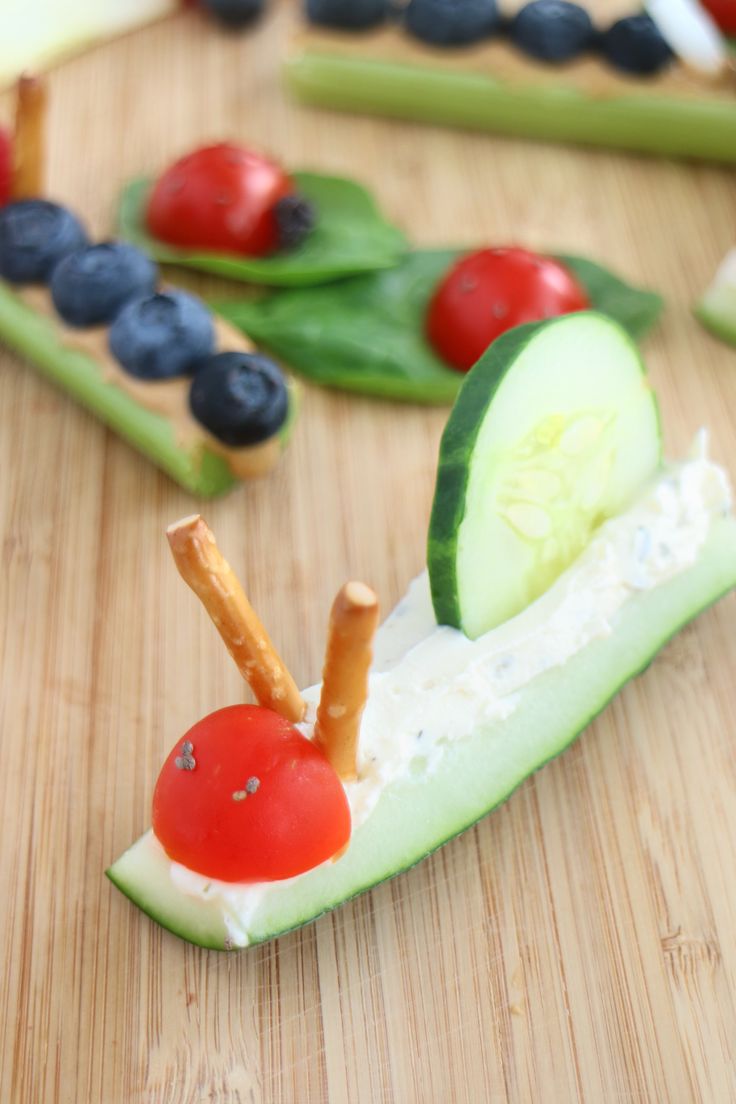 a wooden table topped with cucumber slices, tomatoes and blueberries