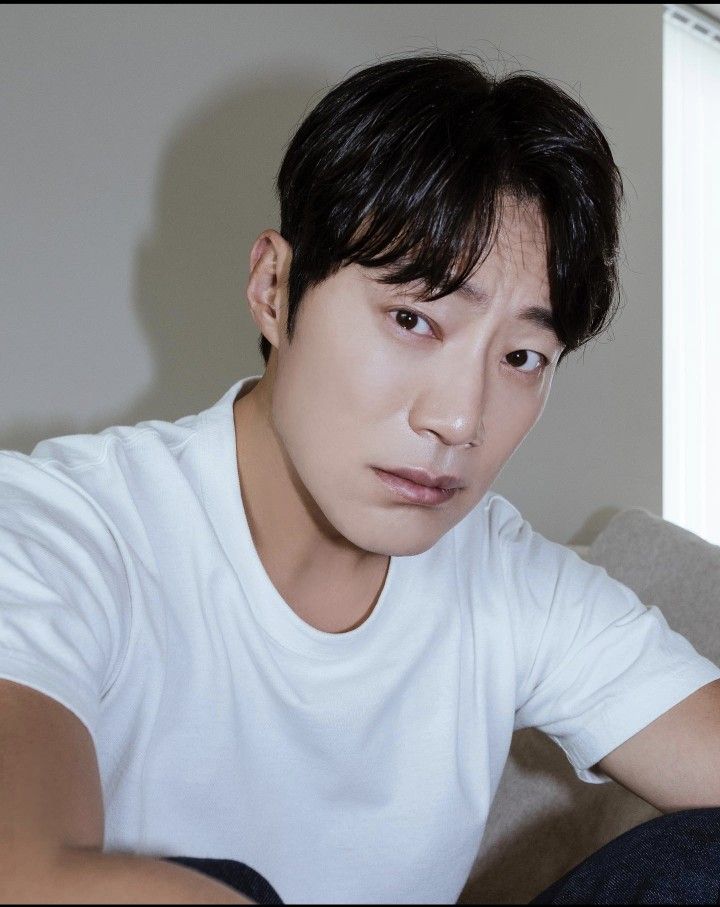 a young man sitting on top of a couch next to a white wall and window