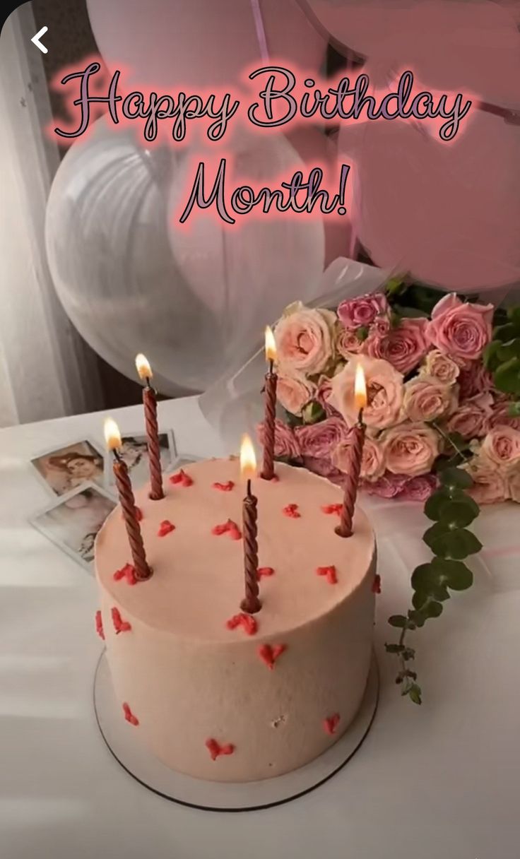 a birthday cake sitting on top of a table next to pink flowers and balloons with the words happy birthday month