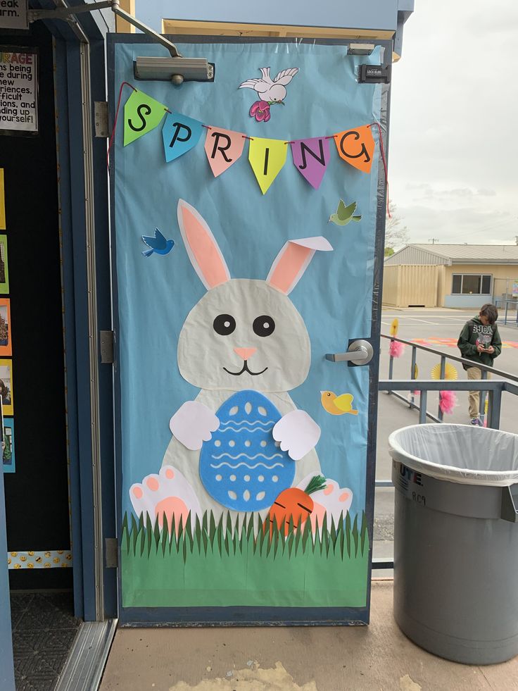 a door decorated with an image of a bunny holding a blue egg in front of a trash can