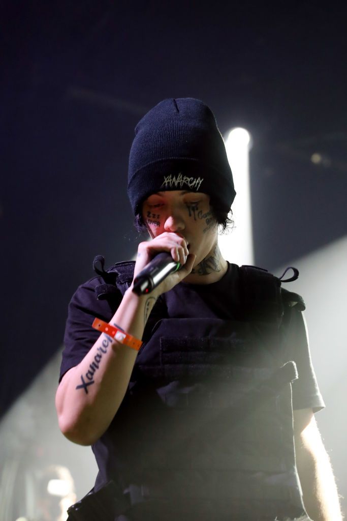 a man in black shirt holding a microphone to his mouth and wearing a beanie