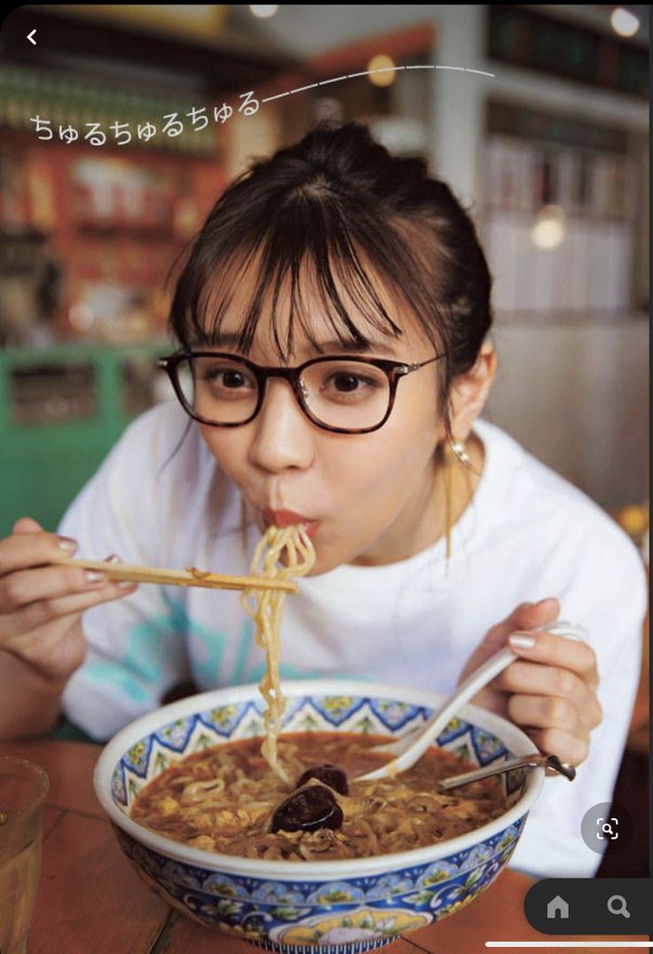 a woman is eating noodles with chopsticks in her mouth