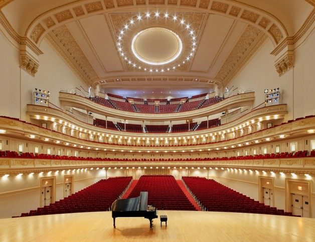 an empty concert hall with a grand piano in the foreground