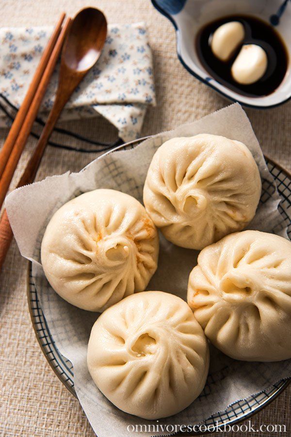 four dumplings on a plate with chopsticks and sauce in the bowl next to them