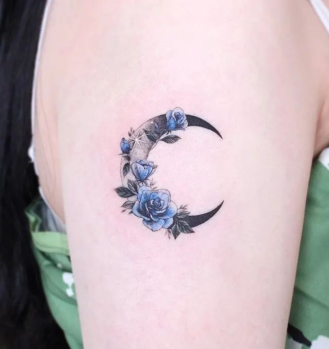 a crescent tattoo with blue roses on it