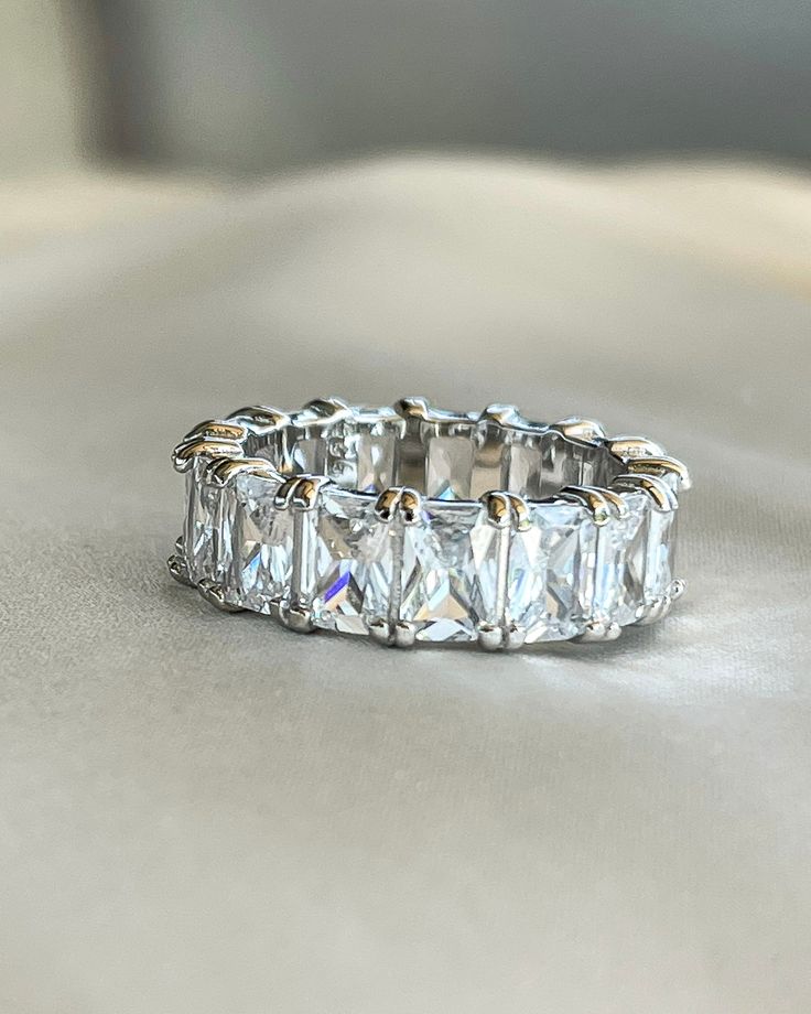 a diamond ring sitting on top of a white cloth covered tablecloth in front of a window