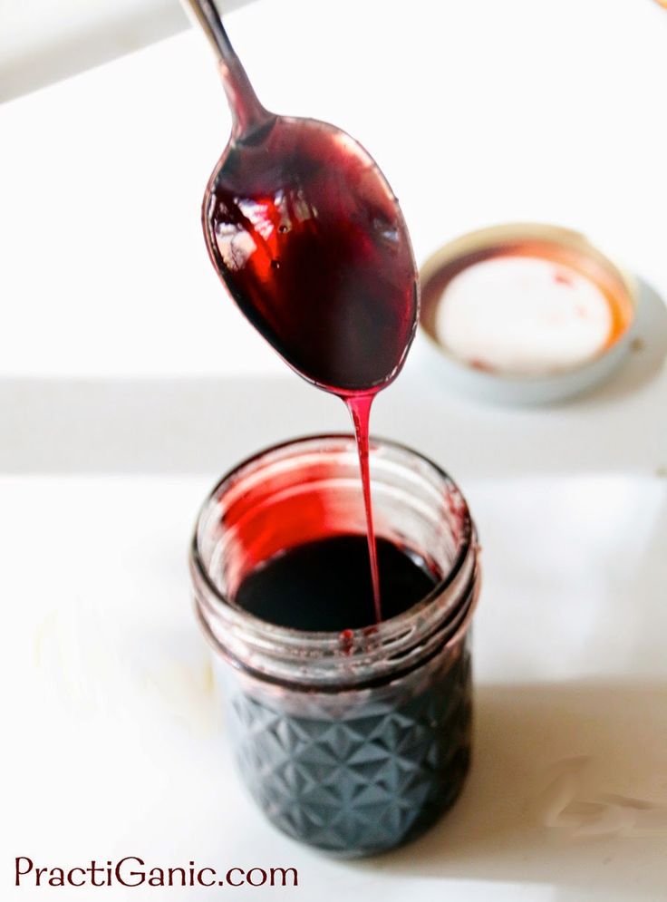 a spoon pouring red liquid into a jar