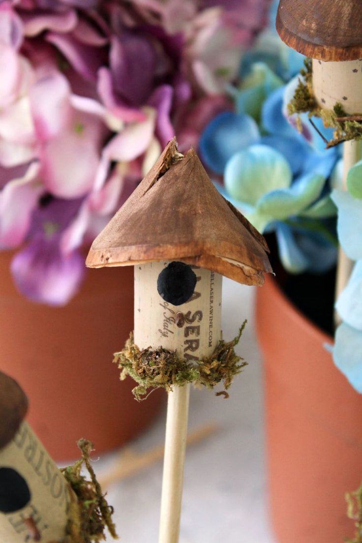 two bird houses on sticks with flowers in the background