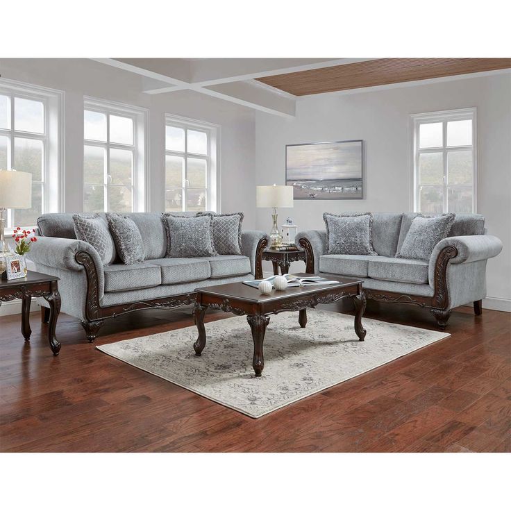 a living room filled with furniture on top of a hard wood floor covered in white rugs