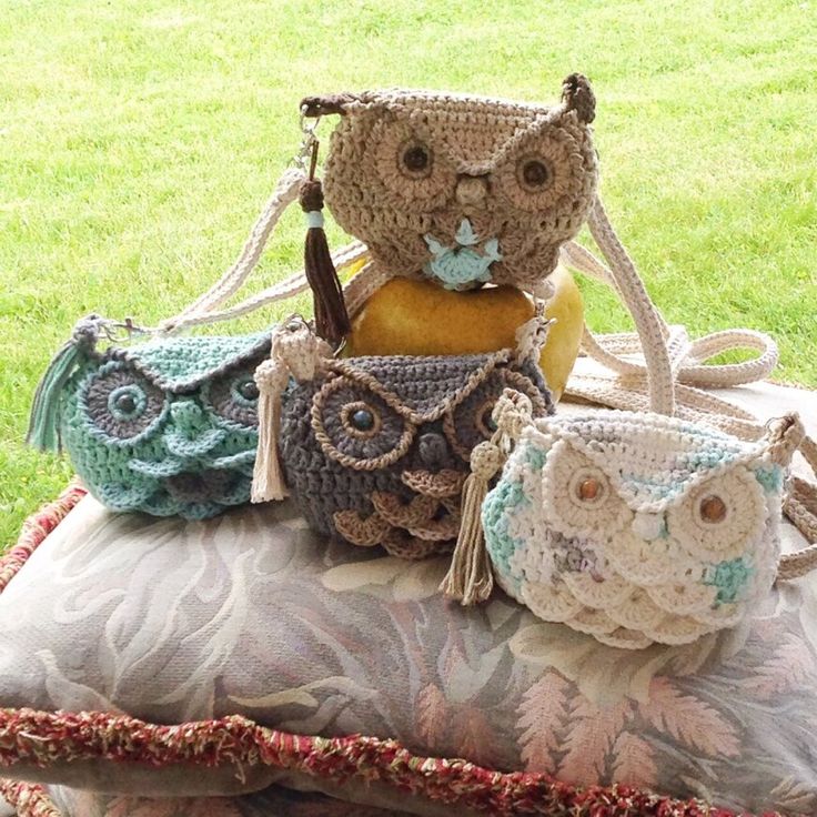 three crocheted owl purses sitting on top of a pillow