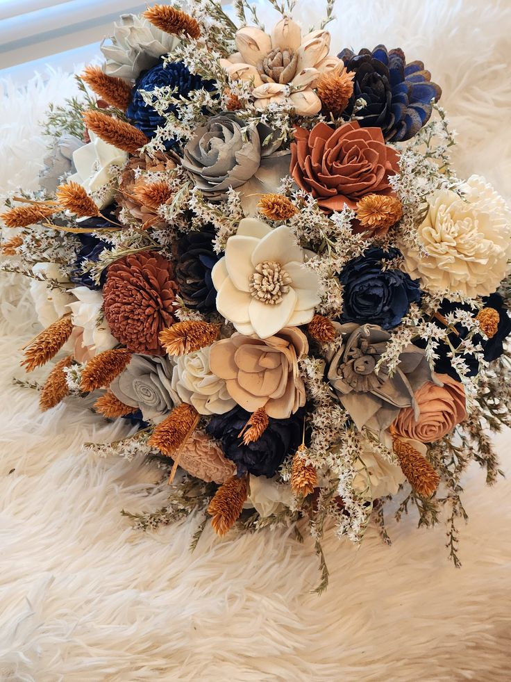 the bridal bouquet is made up of various flowers and foliage, along with feathers