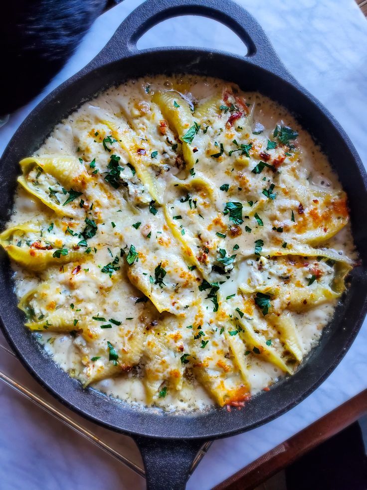 a skillet filled with pasta and cheese on top of a table