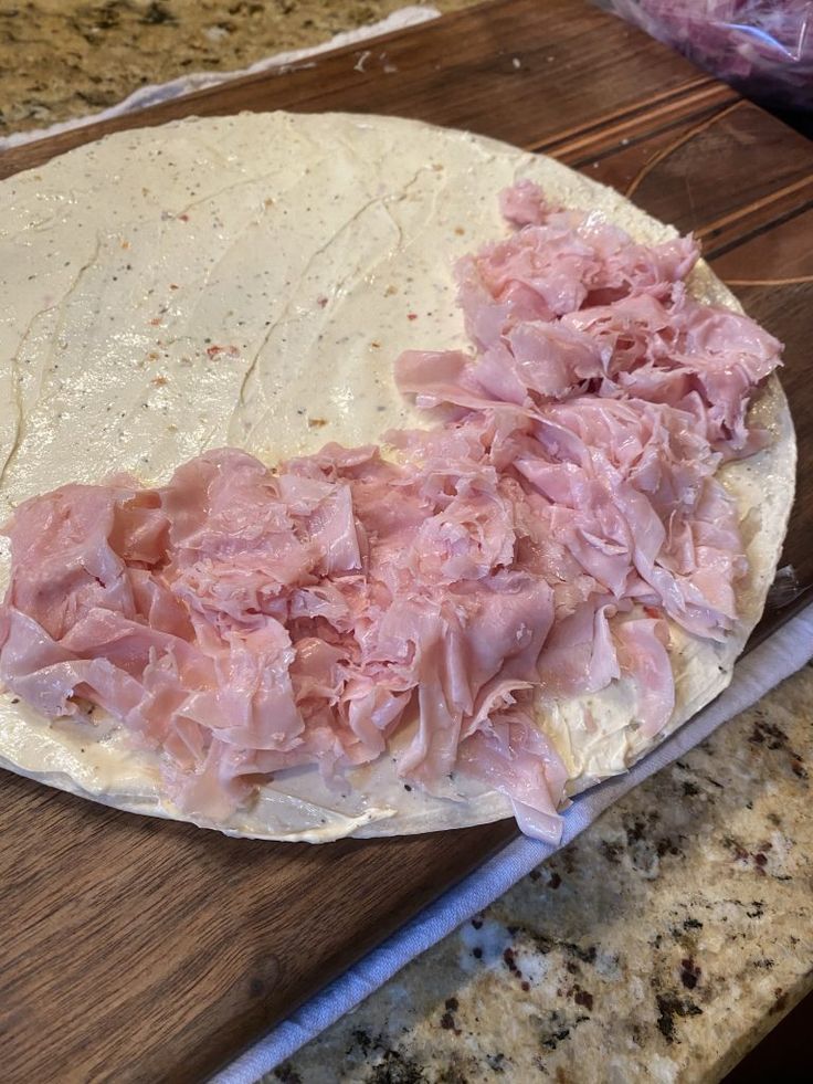 the dough is covered with ham and ready to be made into pizzas or sandwiches