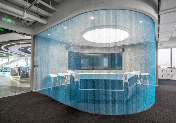 an office with a curved glass wall and blue counter top, in the middle of a conference room