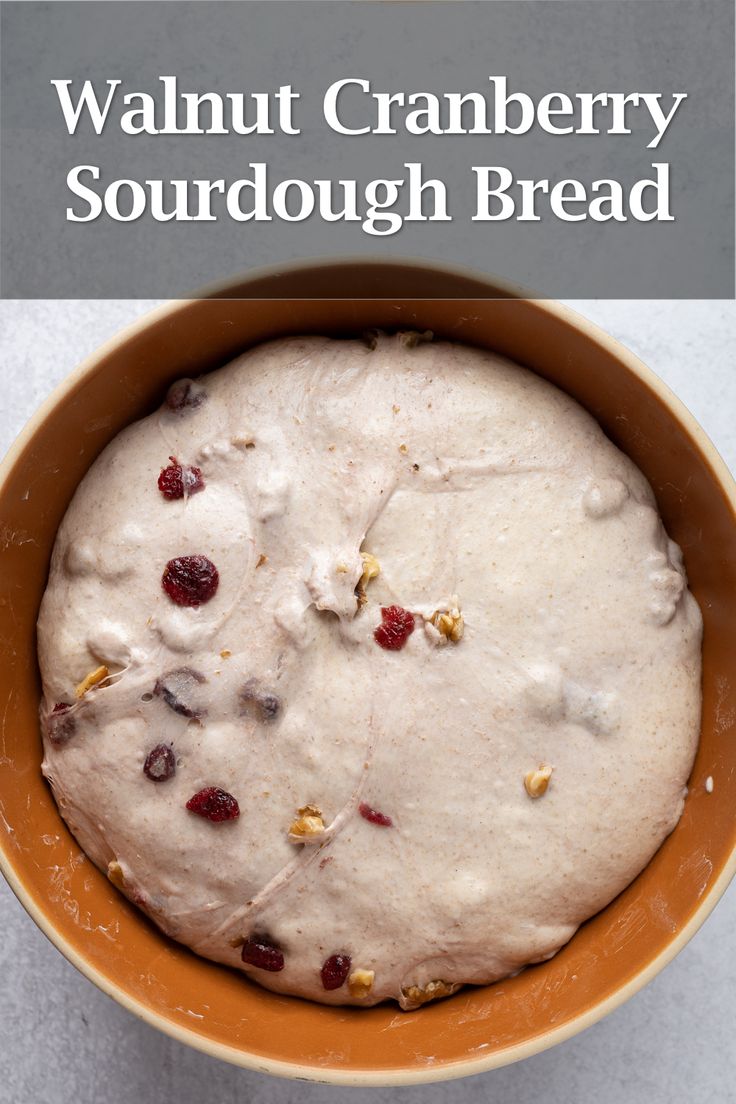 a bowl filled with cranberry sourdough bread on top of a table