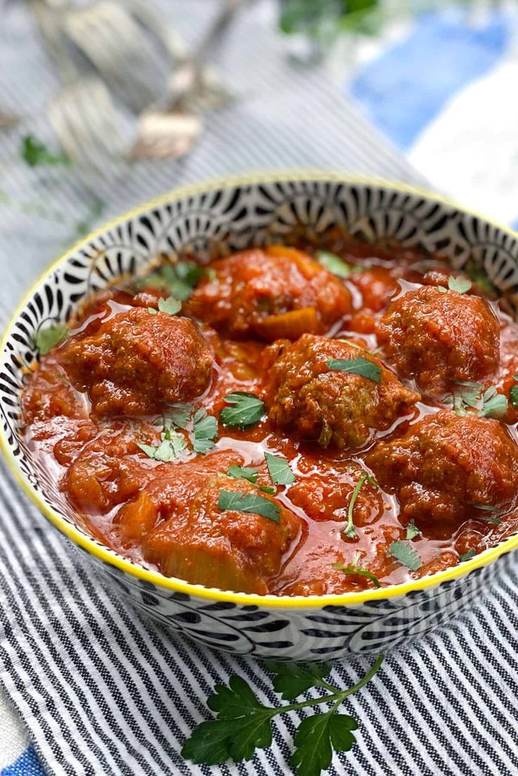 a bowl filled with meatballs covered in sauce and garnished with parsley