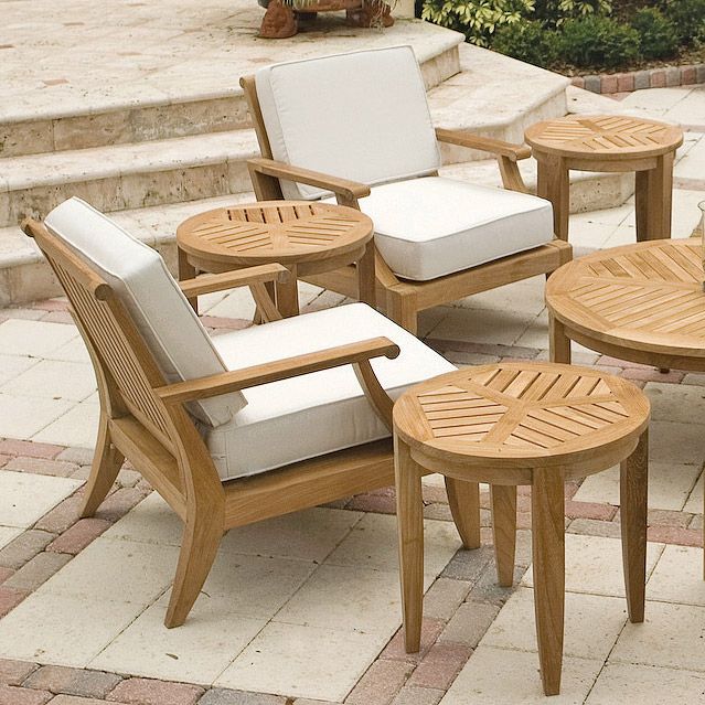 four wooden chairs and two tables with white cushions on the ground near some steps in front of a house