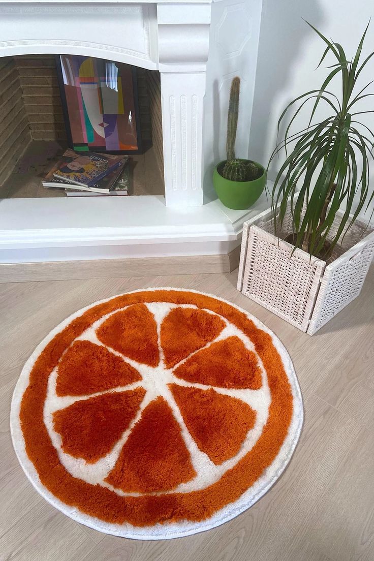 an orange and white rug on the floor next to a potted houseplant