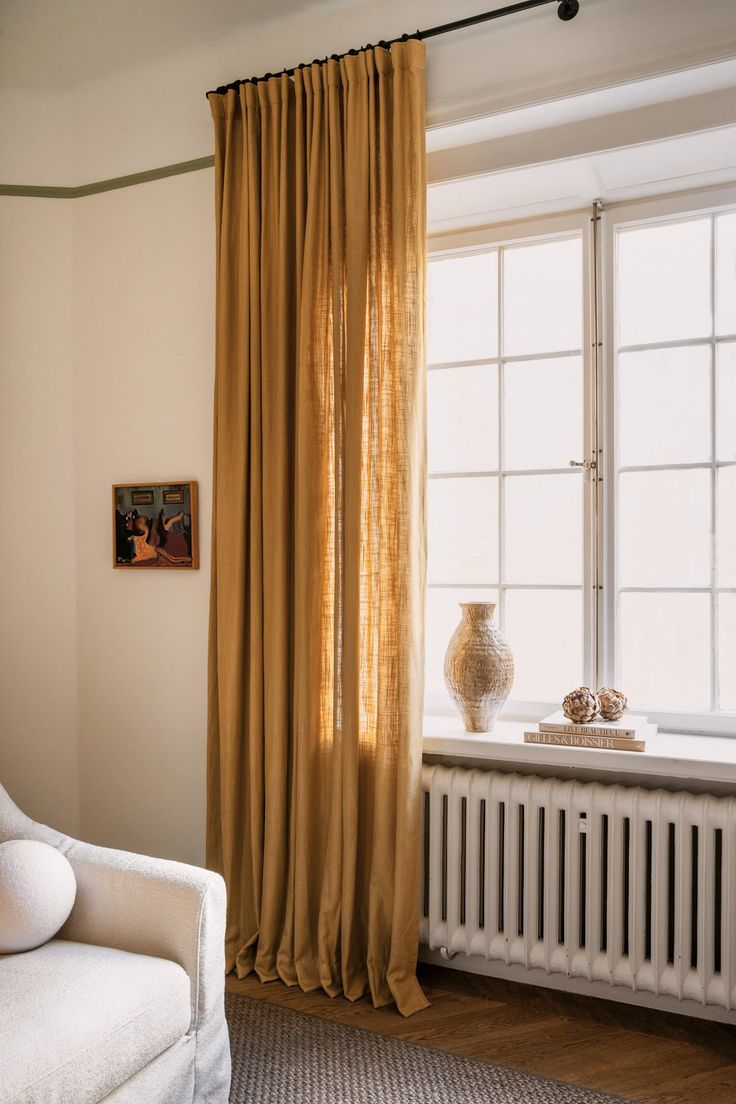 a white chair sitting in front of a window next to a radiator and heater