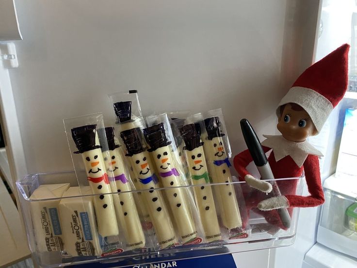 an elf is holding a toothbrush in front of some christmas themed toothpaste