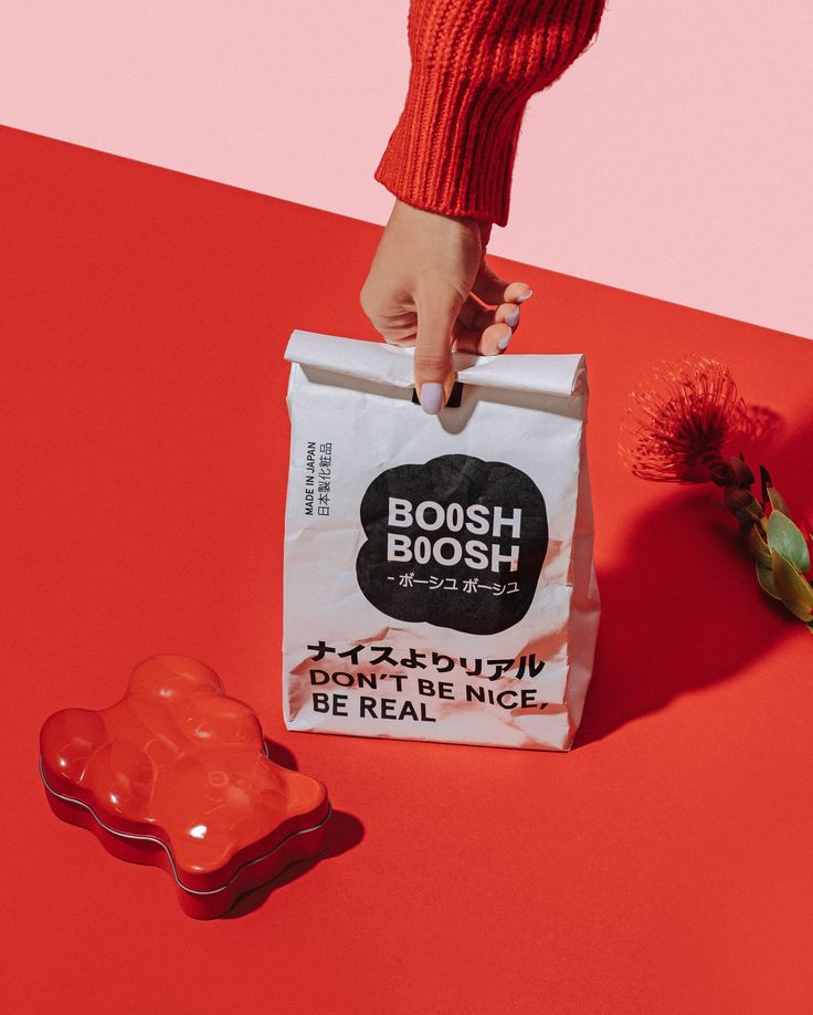 a person's hand reaching into a bag with gummy bears in it on a red and pink surface