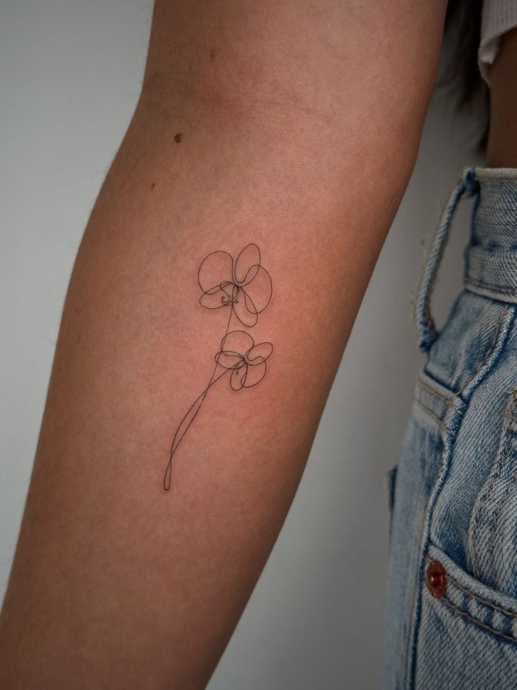 a woman's arm with a single flower tattoo on it