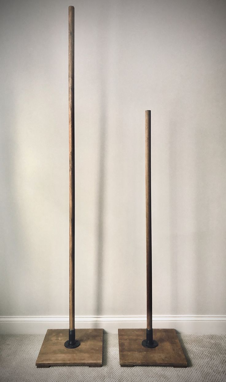 two wooden poles standing on top of each other in front of a white wall and carpeted floor