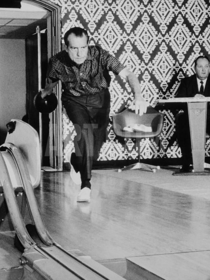 two men in suits and ties are playing bowling on an escalator while another man watches