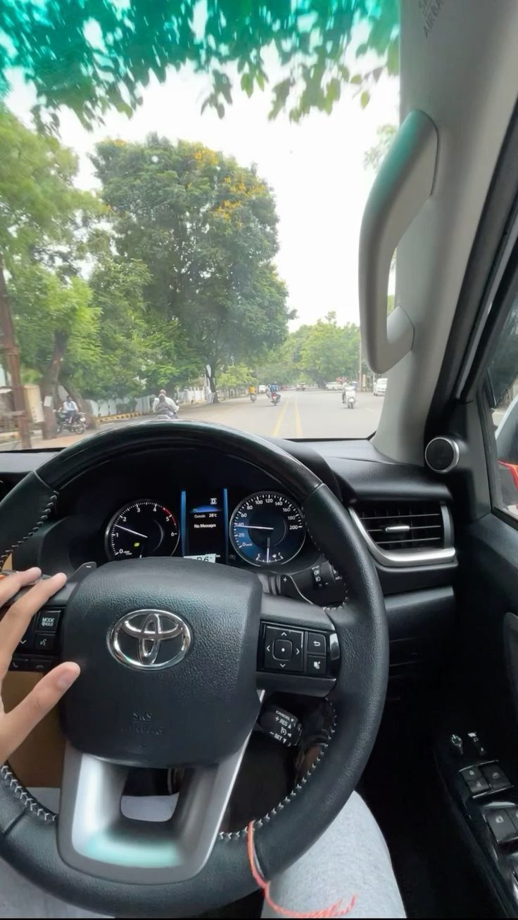 a person driving a car with their hand on the steering wheel