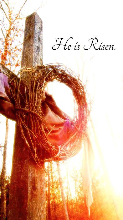 a hand holding a wreath with the words he is risen on it in front of trees