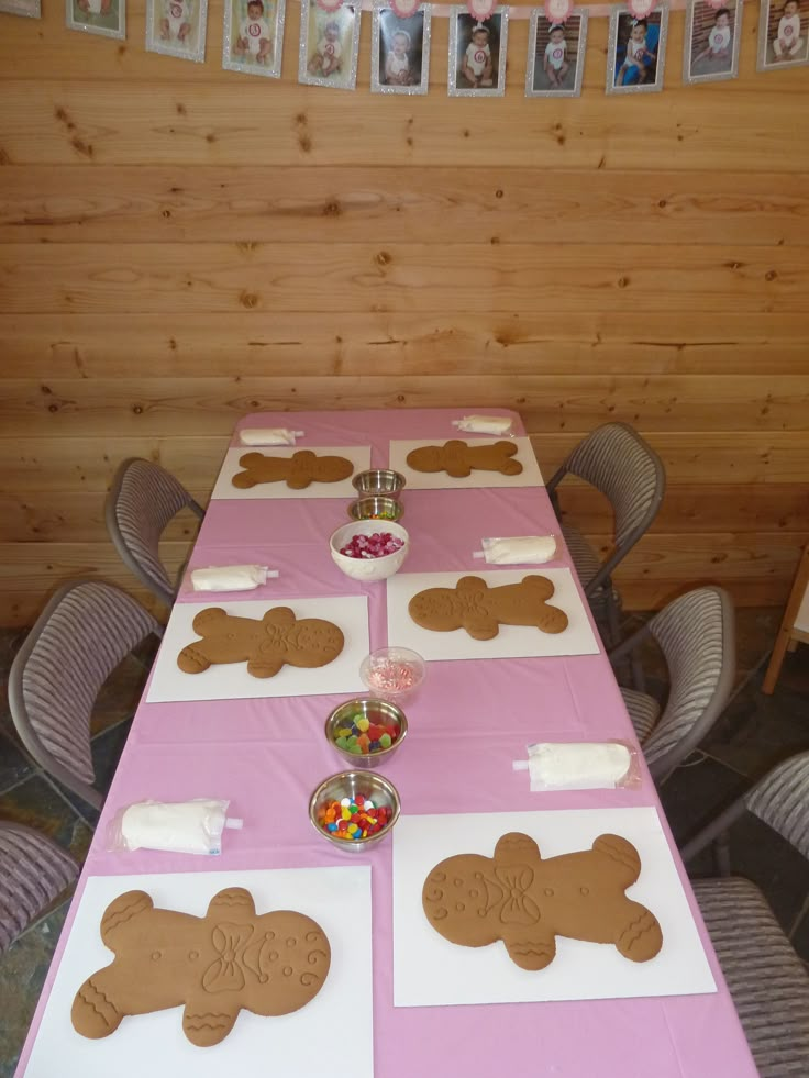 the table is decorated with gingerbreads and candies on pink paper napkins