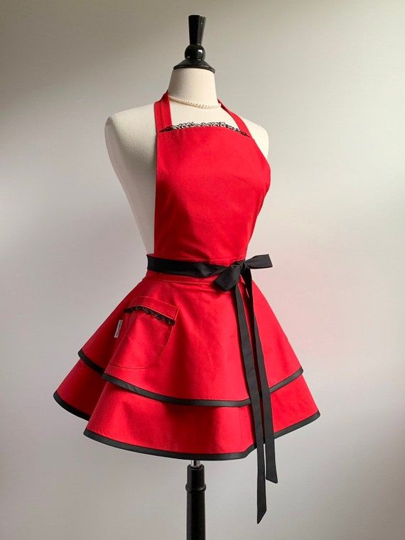 a mannequin wearing a red dress with black trimmings and a bow