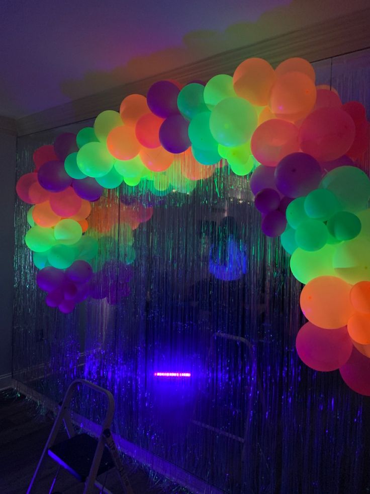 a room filled with lots of balloons hanging from the ceiling and some chairs in front of it