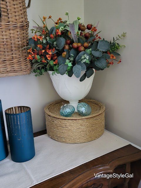 a white vase filled with flowers sitting on top of a table next to two blue vases