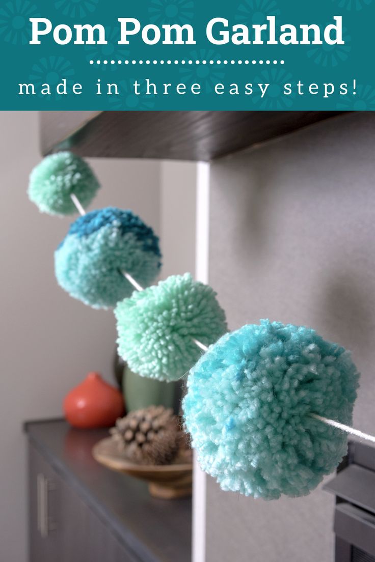 some blue and green pom poms hanging from a line on a shelf in a room