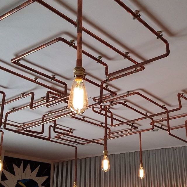 several light bulbs hanging from the ceiling in a room with pipes and wires on it