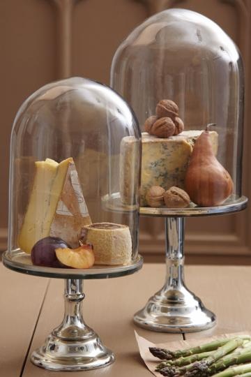 there are two cakes under glass domes on the table with asparagus and cheese