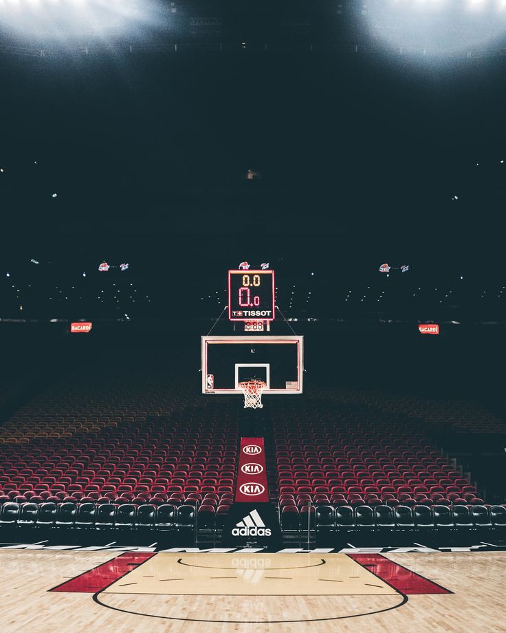 an empty basketball court with red seats