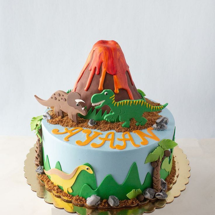 a birthday cake decorated with dinosaurs and volcanos