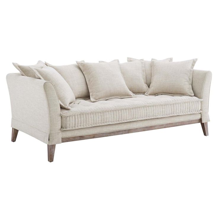 a white couch with many pillows on top of it and a wooden frame around the back