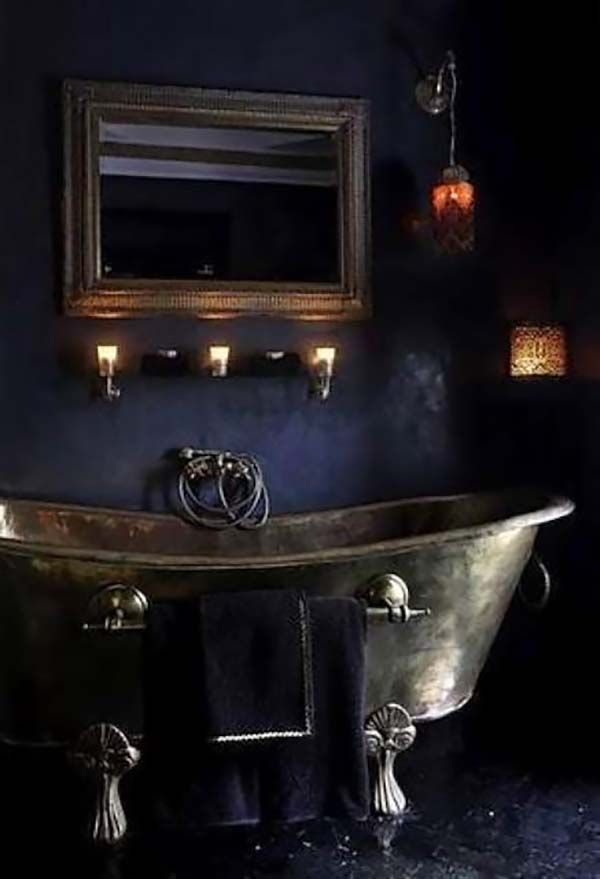 an old fashioned bathtub in a bathroom with candles on the wall and blue walls