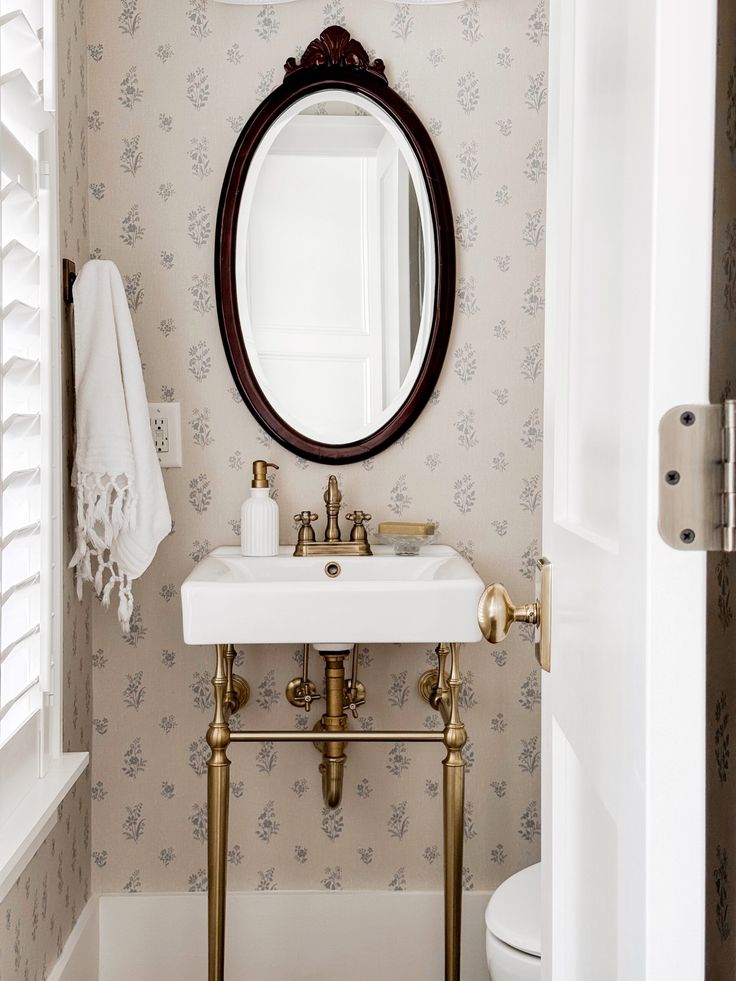 a bathroom with a sink, mirror and toilet paper roll on the wall next to it