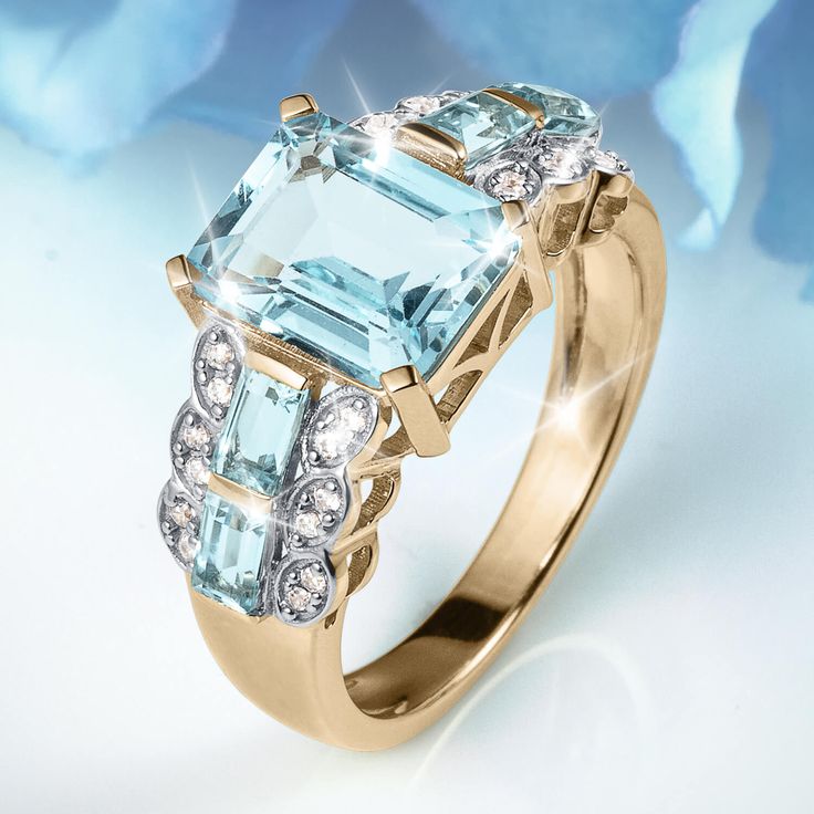 Complement her look with this glamorous gemstone ring. Crafted in sterling silver, finished in 18k yellow gold. This rich design showcases a 4 carat emerald cut, Blue Topaz flanked by trios of princess cut, Blue Topaz and sparkling Diamondeau®, flawless simulated diamond. This style is beautifully poised to become her favorite. Fine Jewelry Asscher Cut Topaz Ring With Accent Stones, Elegant Emerald Cut Topaz Ring With Diamond Accents, Fine Jewelry Emerald Cut Birthstone Ring With Gemstone Accents, Emerald Cut Topaz Ring With Gemstone Accents, Emerald Cut Birthstone Ring With Gemstone Accents, Emerald Cut Topaz Ring With Center Stone, Elegant Topaz Rings With Rectangular Stone, Elegant Birthstone Ring With Rectangular Accent Stones, Elegant Rectangular Birthstone Ring With Accent Stones