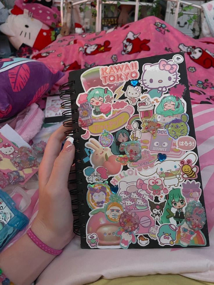 a person is laying in bed with many stickers on their sheets and holding a notebook