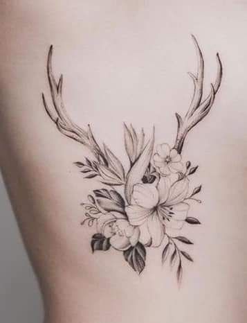 the back of a woman's stomach with flowers and antlers on it